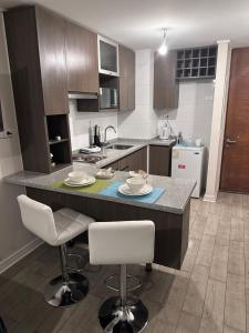 a kitchen with a counter and two bar stools at Depto/2p/Business Trip/Equipado. in Santiago