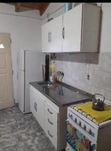 een keuken met witte kasten, een fornuis en een wastafel bij Cabaña Serrana in Santa Rosa de Calamuchita