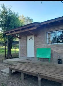 een huis met een groene bank ervoor bij Cabaña Serrana in Santa Rosa de Calamuchita