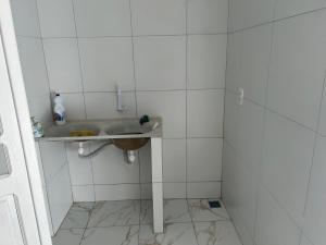 uma casa de banho com um lavatório e paredes em azulejos brancos em Casa união em Olinda