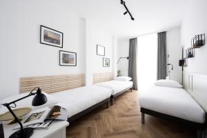 a room with three beds with white walls and wooden floors at Native Apartments Pułaskiego 6 in Kraków