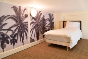 um quarto com uma cama com um mural de palmeiras em Suite Amalfi em Lyon
