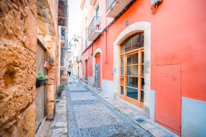 un callejón en un casco antiguo con un edificio rojo en Unik Vacation Civaderia, en Tarragona