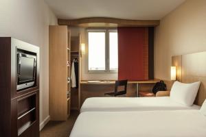 ル・プーザンにあるibis Loriol Le Pouzinのベッド2台とテレビが備わるホテルルームです。