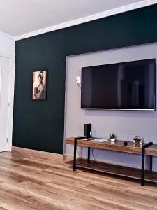 a living room with a large flat screen tv on a wall at Suíte confortável, churrasqueira e TV 55in em area nobre da cidade in Poços de Caldas