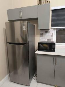 a kitchen with a stainless steel refrigerator and a microwave at KC suites in Government Pen
