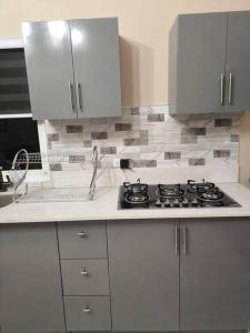 a white kitchen with a stove and a sink at KC suites in Government Pen