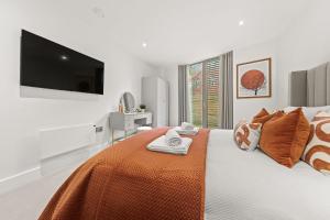 a bedroom with a bed with an orange blanket and a flat screen tv at Atlas House Three in Harrogate