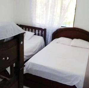 two twin beds in a bedroom with a window at Finca Eccehomo in San Luis