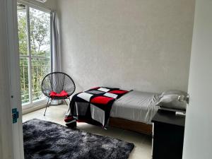 ein Schlafzimmer mit einem Bett, einem Stuhl und einem Fenster in der Unterkunft Departamento 2 habitaciones alberca Luna by Eita in Cancún