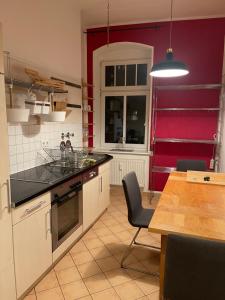 cocina con paredes rojas y mesa con fregadero en Lovely apartment/Prenzlauer Berg, en Berlín