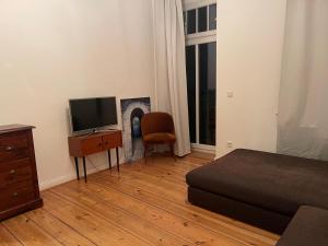1 dormitorio con 1 cama, TV y silla en Lovely apartment/Prenzlauer Berg, en Berlín