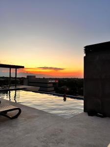 una piscina en la parte superior de un edificio con puesta de sol en Hermoso departamento con piscina y estacionamiento, en Asunción