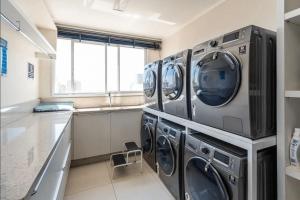 a laundry room with three washing machines and a window at Studios Modernos no Setor Bueno WBU in Goiânia