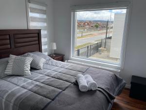 a bedroom with a bed with two pillows and a window at Departamento manantiales 1 in Punta Arenas