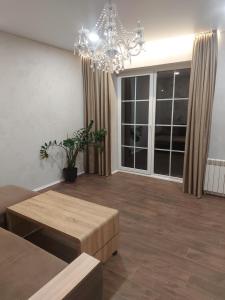 ein Wohnzimmer mit einem Kronleuchter, einem Sofa und Tischen in der Unterkunft Apartamentai poilsiui in Telšiai