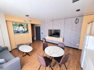 sala de estar con 2 mesas, sillas y TV en Apartament Best View - Endless Summer Mamaia Nord Apartaments, en Mamaia Nord – Năvodari