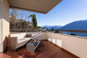 einen Balkon mit einem Sofa, einem Tisch und Bergen in der Unterkunft Sonnenschein in Brione sopra Minusio