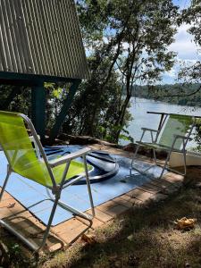 einem grünen Stuhl auf einer Terrasse neben einem Boot in der Unterkunft Refúgio Iguassu chalé com tranquilidade entre o Rio Iguaçu e o Parque Nacional in Capanema