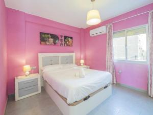a pink bedroom with a white bed and a window at Málaga Capital cerca de la Playa in Málaga