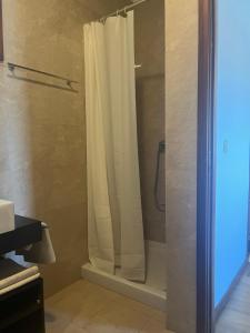 a shower with a white shower curtain in a bathroom at Sea Breeze - BeachHouse in Mindelo