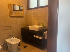 een badkamer met een wastafel, een toilet en een spiegel bij Sea Breeze - BeachHouse in Mindelo
