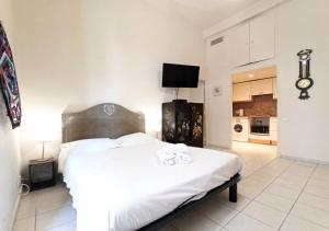 Cet appartement comprend une chambre avec un grand lit blanc et une cuisine. dans l'établissement Viva Riviera Residence Marina Croisette, à Cannes