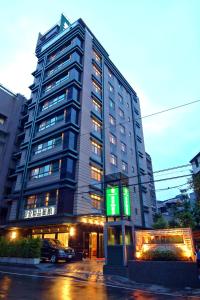 un edificio alto con una señal verde delante de él en Jingan Classic Inn en Zhonghe