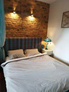 a bedroom with a white bed with a brick wall at Art Illery Apartment in Riga