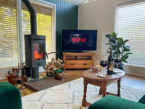 a living room with a wood stove and a tv at Green Vale Lodge, Yanwath, Ullswater in Tirril
