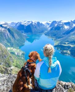 a woman and her dog sitting on top of a mountain at Flo Bellevue in Stryn