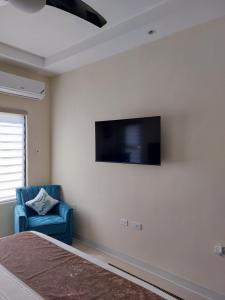 a bedroom with a bed and a blue chair and a television at PYRAMID JOY, 2 Bedroom Villa, Ocho Rios, Jamaica in Ocho Rios
