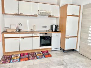 a kitchen with white cabinets and a kitchen rug at Casa Giulia 2 Zimmer, Küche, Bad, WLAN, Parkplatz in Gleiberg