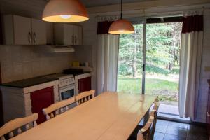 cocina con mesa de madera, sillas y ventana en Casa de Campo en Oceanía en Rincón de los Oliveras