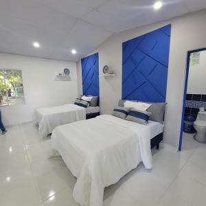 ein Schlafzimmer mit 2 Betten und einer blauen Wand in der Unterkunft RANCHO SARIMAR in La Libertad