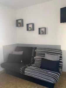 ein schwarzes Sofa in einem Zimmer mit Bildern an der Wand in der Unterkunft Les marines d'helios in Le Castellas
