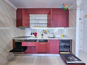 a kitchen with red cabinets and a sink at 7Lizards - Ocean View Apartments in Puerto de Santiago