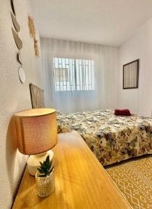 um quarto com uma cama e uma mesa com um candeeiro em LC Apartaments Hospital General em Castellón de la Plana