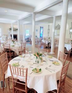 un salón de banquetes con mesas y sillas blancas en The Grenville Hotel and Restaurant, en Bay Head