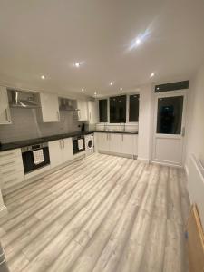 duża kuchnia z drewnianą podłogą i białymi szafkami w obiekcie 15 min to Central London Guest Suites 22 w Londynie