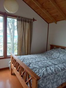 een slaapkamer met een bed en een groot raam bij Cabaña Isla de los Pájaros in Ushuaia