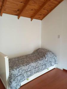 een klein bed in een kamer met een houten plafond bij Cabaña Isla de los Pájaros in Ushuaia