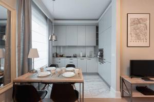 a kitchen with a table and chairs in a room at Cozy, bright apartment. Swimming pool, parking, gym, PREMIUM in Warsaw