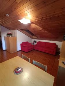 uma sala de estar com uma mesa e dois sofás vermelhos em [Aprica 4 min. piste baradello] em Aprica
