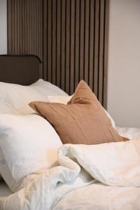 an unmade bed with white sheets and brown pillows at Hotel feeling in the center of Trondheim in Trondheim