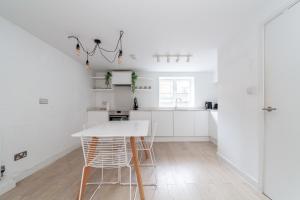 a white kitchen with a white table and chairs at Two Bedroom Belgravia Charm in London