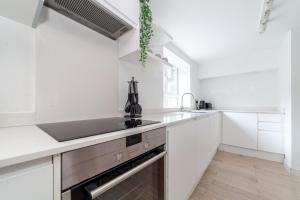 a white kitchen with a sink and a stove at Two Bedroom Belgravia Charm in London