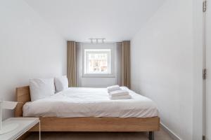 a bedroom with a bed with white sheets and a window at Two Bedroom Belgravia Charm in London
