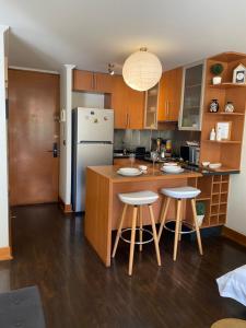 uma cozinha com uma ilha com bancos e um frigorífico em Departamento en el corazón de Providencia em Santiago
