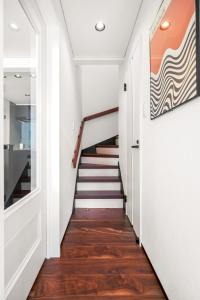 a staircase in a house with white walls and wood floors at Best Location LUX Home, 2 Blocks to Sbwy, Sleeps 9 in Sapporo